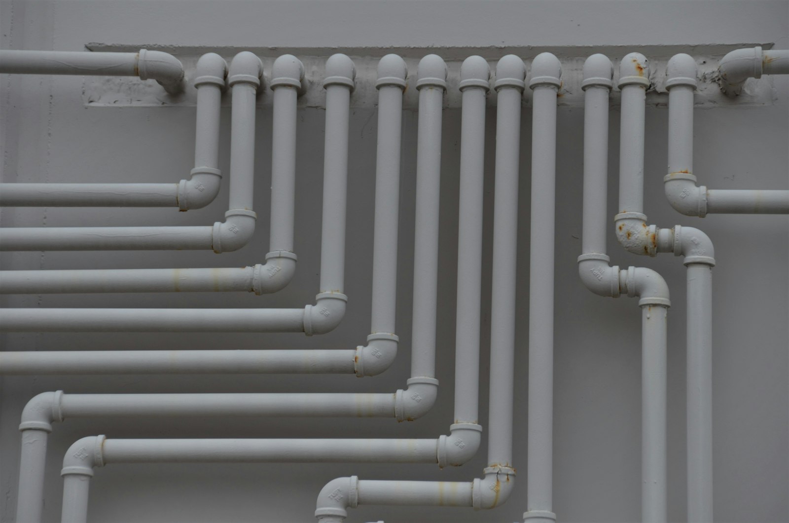 Rows of white water pipes mounted on a wall